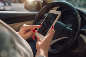 Uber accident lawyer San Fernando Valley CA - Mockup image of woman hand using mobile smartphone with blank screen while driving car and leaving home. clipping path.