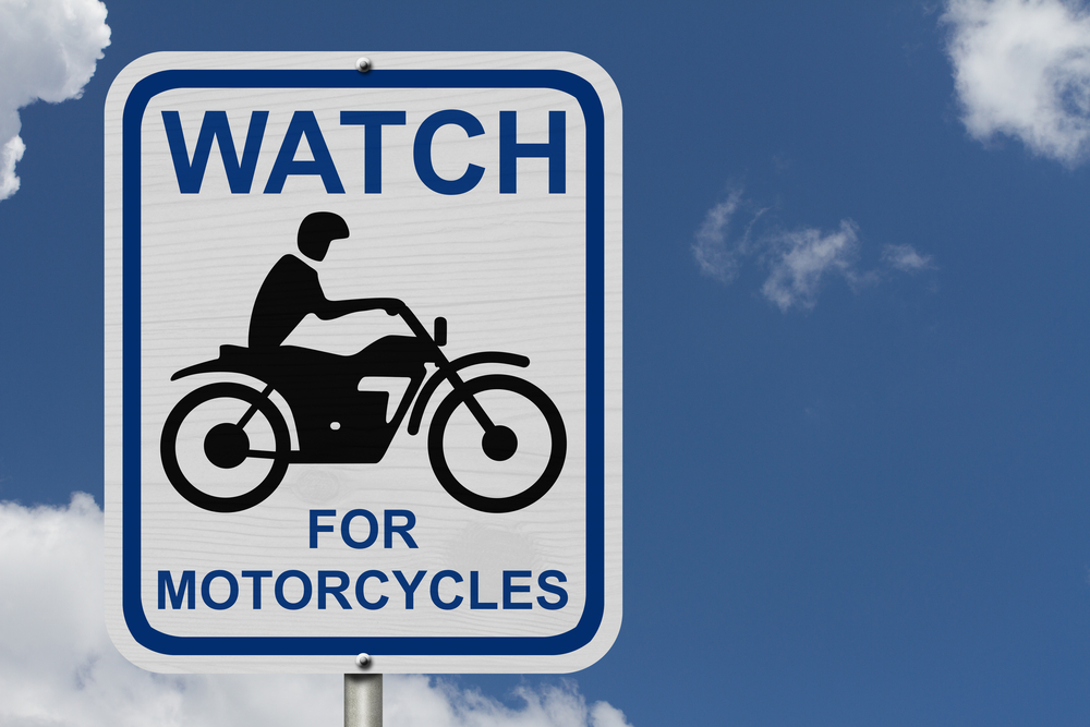 Motorcyclist Fatally Injured In Hit-and-Run Accident - Watch For Motorcycles Warning Sign, An road warning sign with words Watch For Motorcycles and a motorcycle icon with blue sky background